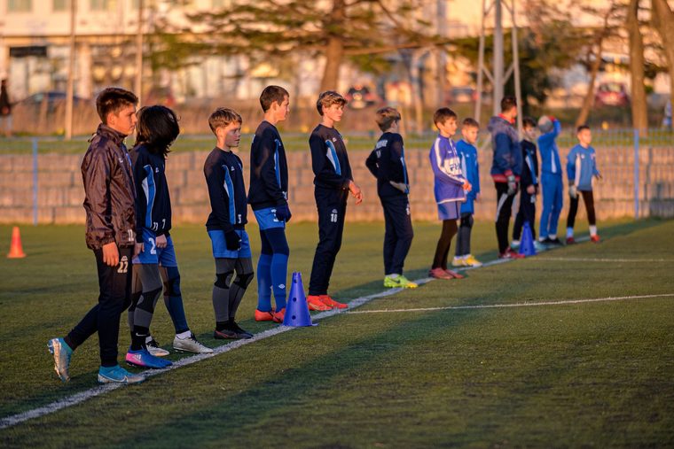Equipo infantil alineado en un campo municipal durante un entrenamiento.